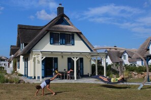 A house with a thatched roof, a covered patio, and a hammock. - Thatched House Anchorage (Zierow)