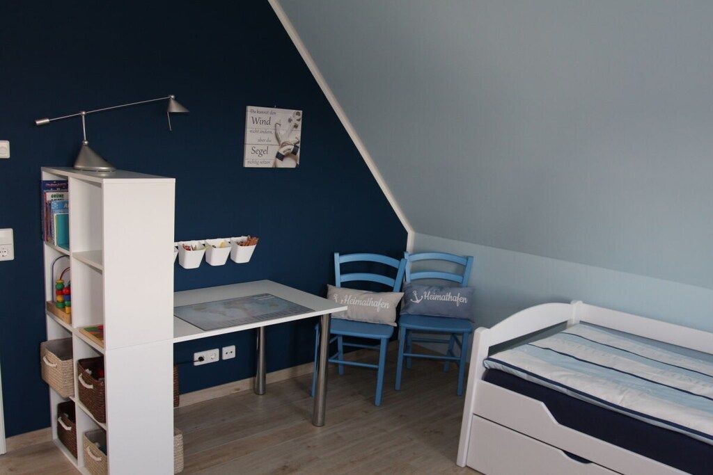 A child's bedroom with a bunk bed, a desk with a lamp, and a bookshelf.