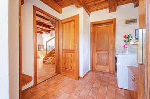 Un pasillo con puertas de madera, una escalera y una zona de cocina con lavadora.