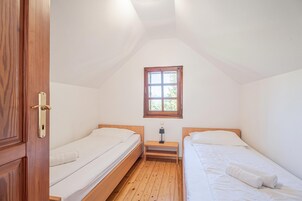 Un alojamiento pequeño con una sola habitación, dos camas, un ventanal y una puerta de madera.
