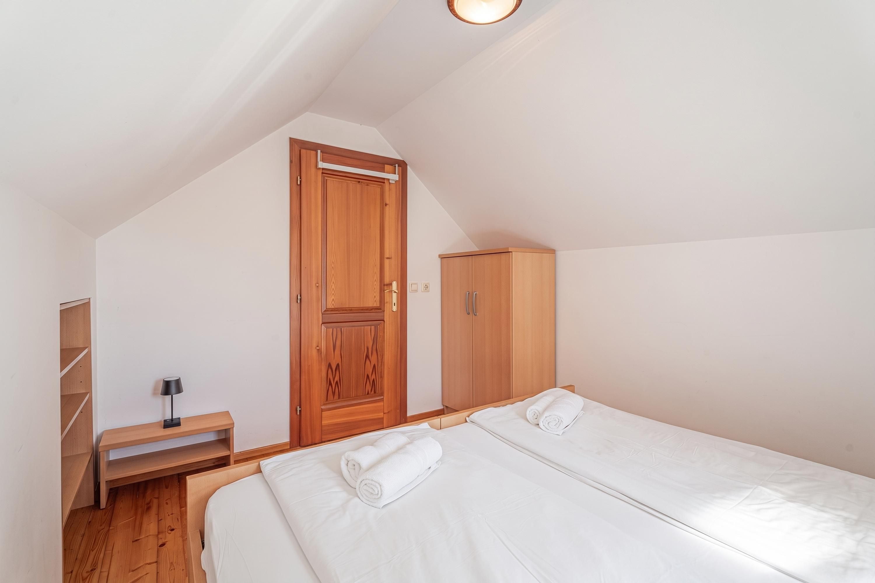 Un dormitorio con dos camas, un armario de madera, un escritorio con lámpara y una puerta.
