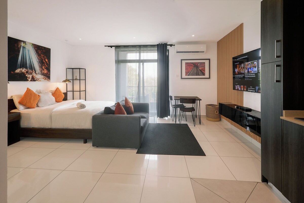Ein modernes Hotelzimmer mit Bett, Sofa, Fernseher und Essbereich.