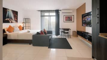 Ein modernes Hotelzimmer mit Bett, Sofa, Fernseher und Essbereich.