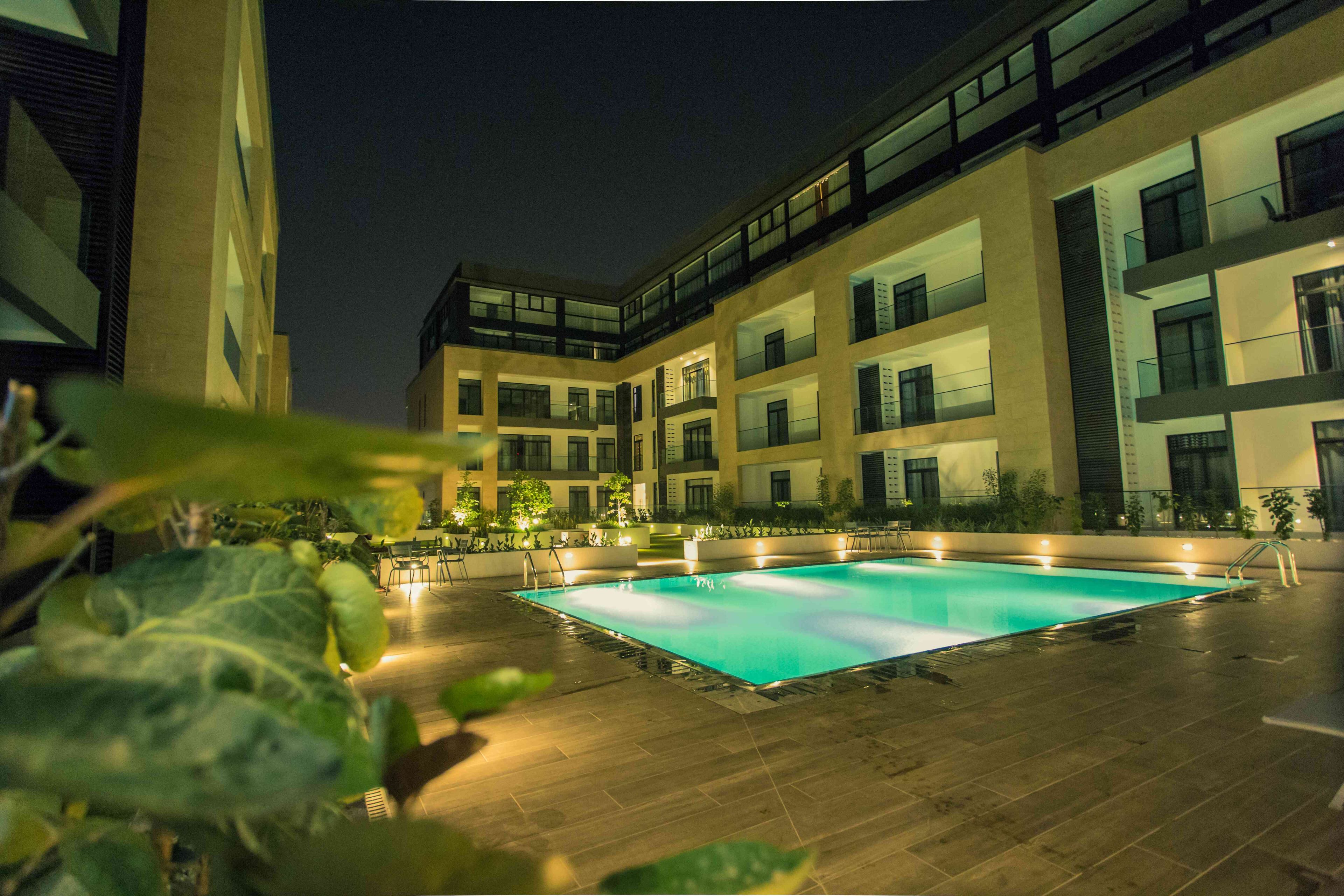 Un edificio moderno con piscina, varios balcones y zonas de estar al aire libre.