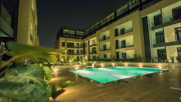 Un edificio moderno con piscina, varios balcones y zonas de estar al aire libre.