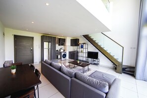 Un espacio habitable moderno con comedor, sofá, cocina y escalera.