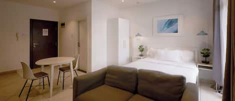 Une chambre d’hôtel comprenant un lit, un canapé, une table à manger avec des chaises, un petit bureau et une porte avec une pancarte.