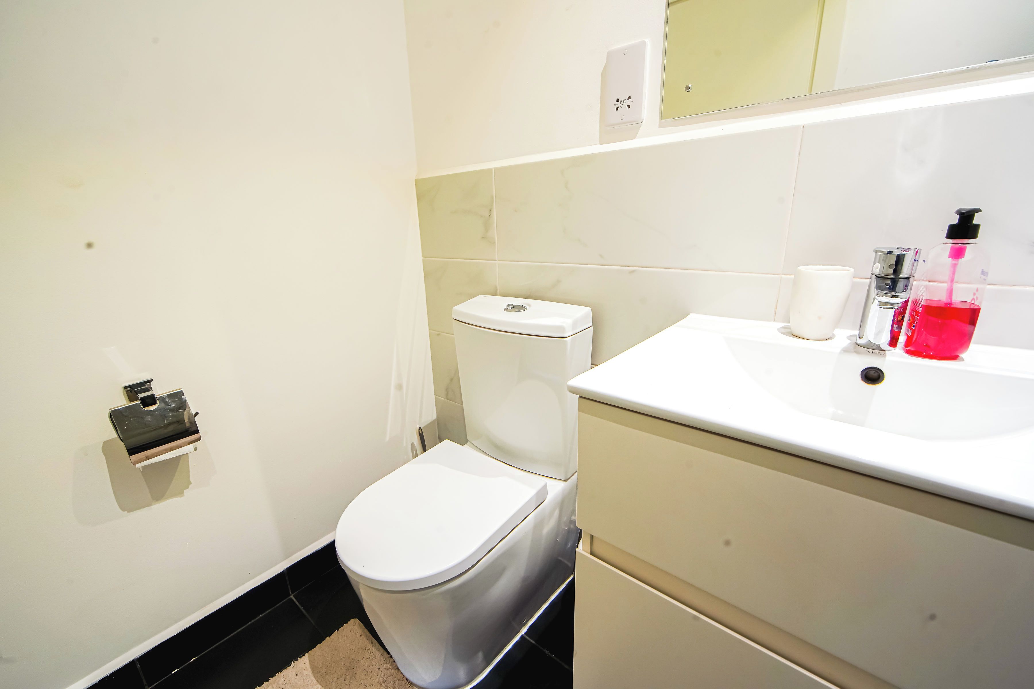 A modern bathroom with a toilet, sink, and mirror.