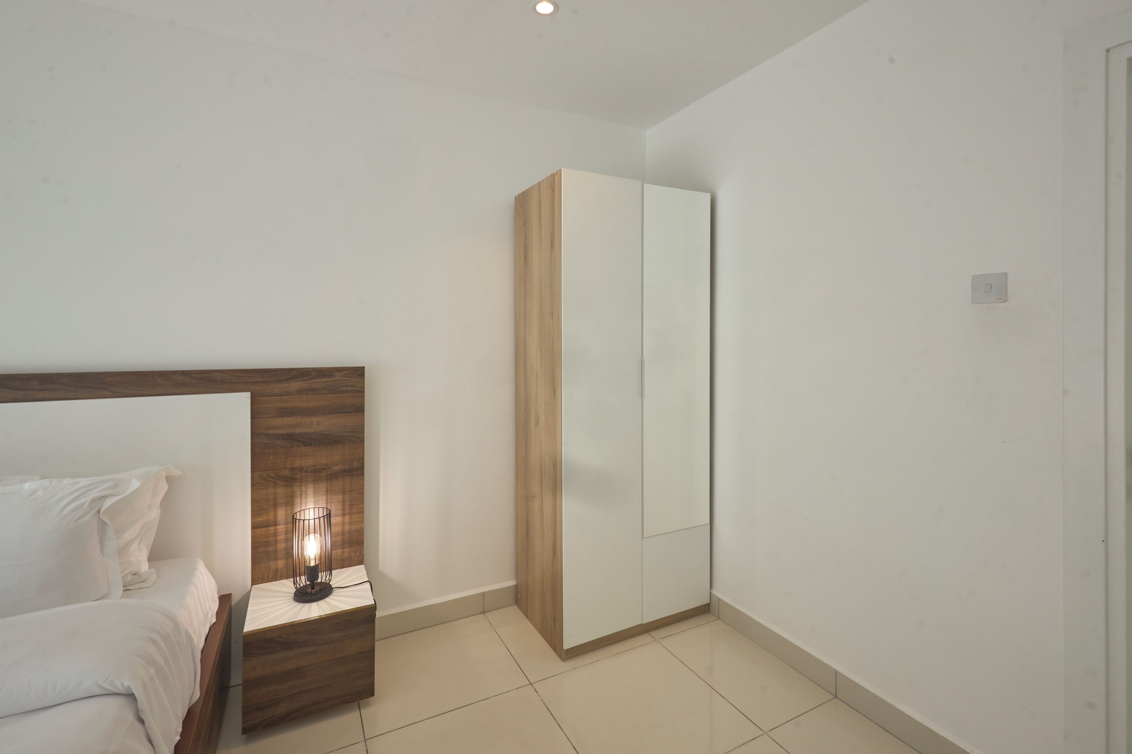 A bedroom with a bed, nightstand, and wardrobe.