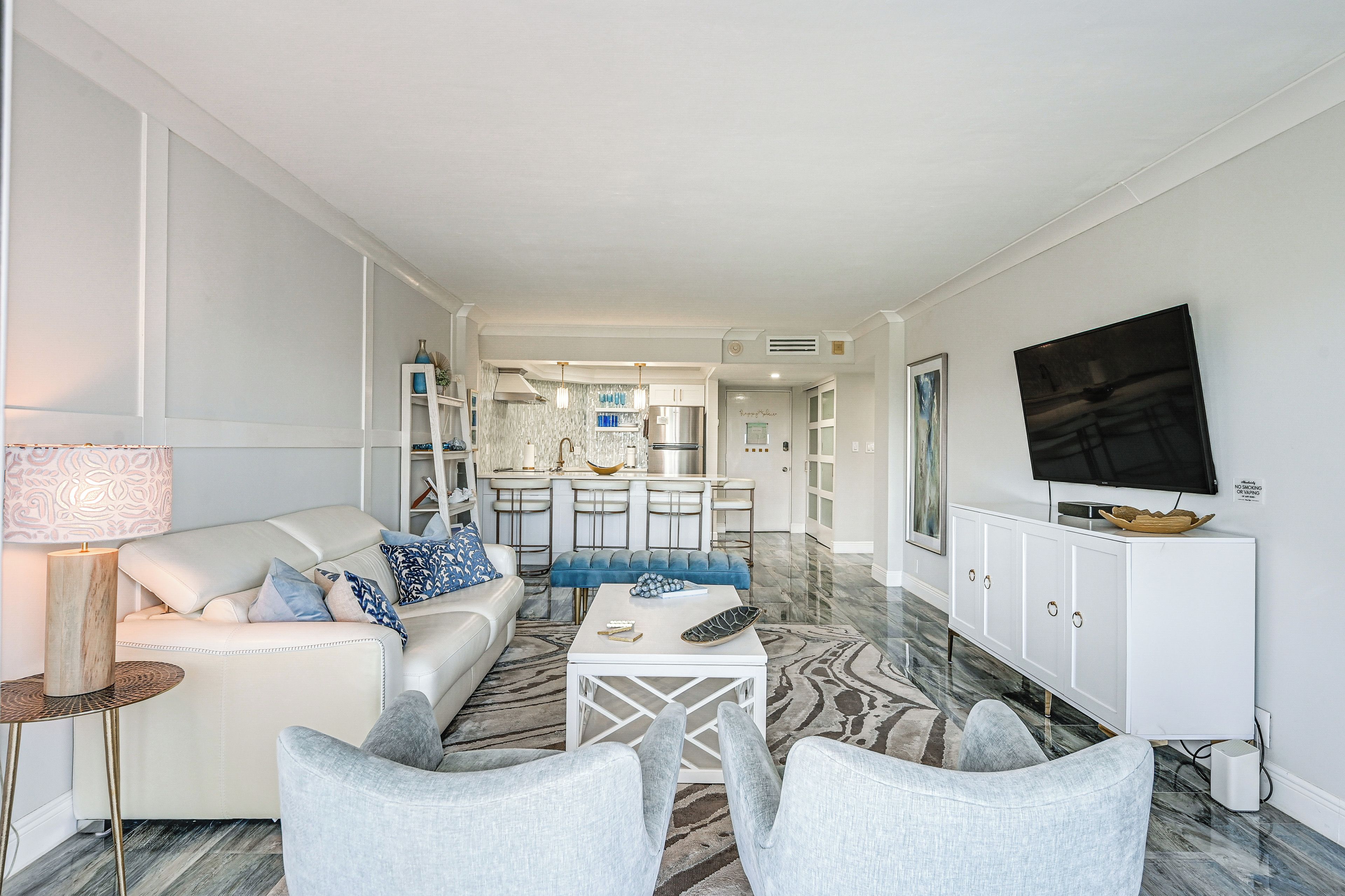 Un salon moderne avec un canapé, des fauteuils, une table basse et un téléviseur.
