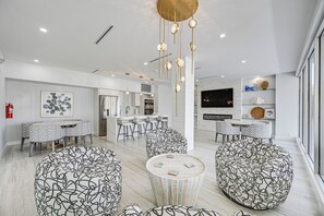 Ein modernes Wohnzimmer mit einem zentralen Couchtisch, gemusterten Hocker und einer Küchenzeile mit Barhocker.