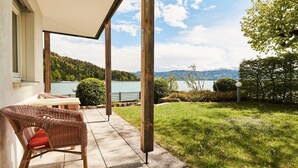 A patio with a view of a lake and mountains, a wicker chair, and a table. - No. 1 - The Lake House (Walchensee)