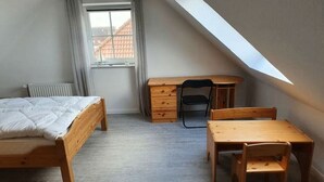 A bedroom with a bed, a desk, and a chair. - Holiday home with 3 bedrooms (Dornumersiel)