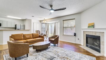 Ein Wohnzimmer mit einem braunen Ledersofa, einem runden Couchtisch und einem gemusterten Teppich.