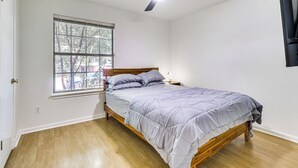 Una camera da letto con un letto, una finestra, una ventola a soffitto e un comodino.