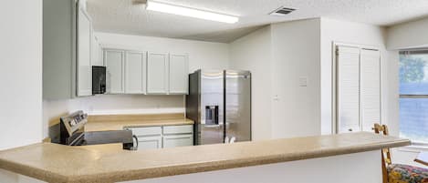 A kitchen with white cabinets, a stainless steel refrigerator, and a granite countertop.