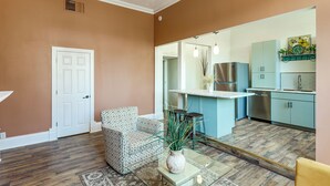 Una cocina moderna con refrigerador incorporado, un lavamanos y una zona de comedor con mesa de vidrio y dos sillas.