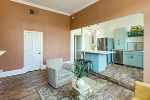A modern kitchen with a built-in fridge, a sink, and a dining area with a glass table and two chairs.