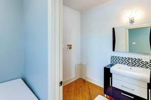 Um banheiro com pia branca, espelho com moldura decorativa e painel de azulejos.