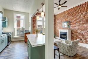 A kitchen with a large island, a dining area with a brick wall, and a fireplace.