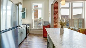 Una cocina moderna con electrodomésticos de acero inoxidable, piso de madera y un ventanal con vistas al exterior.