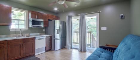 A kitchen with a microwave, oven, refrigerator, and a ceiling fan.