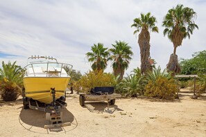 Un bateau jaune, posé sur une remorque, dans un désert parsemé de palmiers.