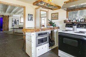 A kitchen with a wooden countertop, a stove, and a large mirror. - Pool, Spa & Stargazing! Private Desert Retreat (Twentynine Palms)