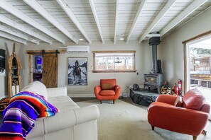Un salon avec un canapé blanc, un fauteuil rouge et une cheminée.