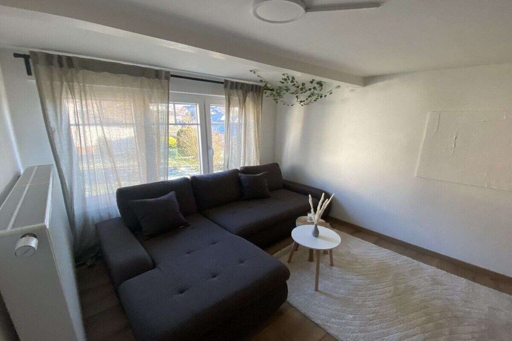 A modern living room with a sectional sofa, a small round table, and a view of the outdoors.