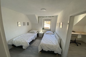 Ein Schlafzimmer mit zwei Einzelbetten, einem Schreibtisch und einem Stuhl.
