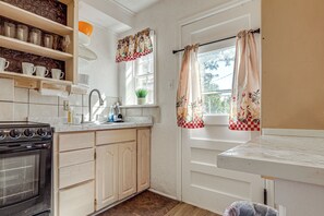 Een keuken met een fornuis, spoelbak en kastjes.
