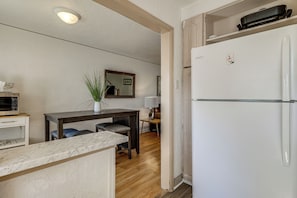 A compact kitchen with a refrigerator, a dining table with chairs, and a small countertop.
