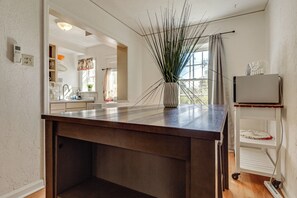 Een keuken met een houten aanrecht, een vaas met groene planten en uitzicht op de eetruimte.