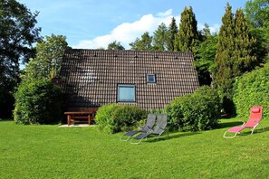 Une maison avec un toit en tuiles, une fenêtre et un banc dans la cour.