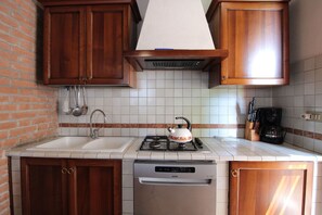 A kitchen with wooden cabinets, a white sink, a gas stove, and a dishwasher. - Vacation Home in Chioggia with 2 bedrooms sleeps 5 (Chioggia)