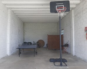 A basketball hoop labeled 'TARMAK' in a garage with a table, bicycle, and a wooden cabinet. - Vacation Home in Chioggia with 2 bedrooms sleeps 5 (Chioggia)