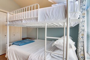 Ein Stockbett mit weißer Bettwäsche und einer blauen Decke.