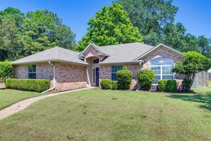 A two-story brick house with a covered front porch, a garage, and a well-maintained lawn.