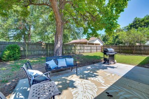 Ein Garten mit Holzzaun, einer Bank, einem Grill und einem Haus im Hintergrund.