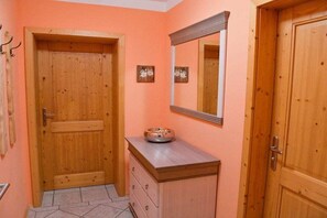A wooden door, a mirror, and a small cabinet with a bowl on top. - Holiday apartment with 1 bedroom (Salzweg)