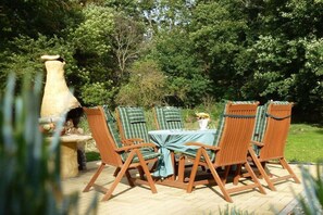An outdoor patio with a round table and chairs, surrounded by greenery. - ||---------------------"Haus Waldesruh"------------------|| (Elbingerode)