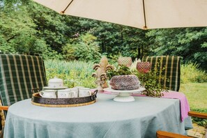 An outdoor dining area with a table set for tea service, surrounded by lush greenery. - ||---------------------"Haus Waldesruh"------------------|| (Elbingerode)