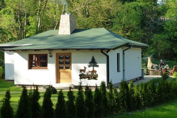 A small white building with a green roof, a chimney, and a deer and tree emblem on the wall. - ||---------------------"Haus Waldesruh"------------------|| (Elbingerode)