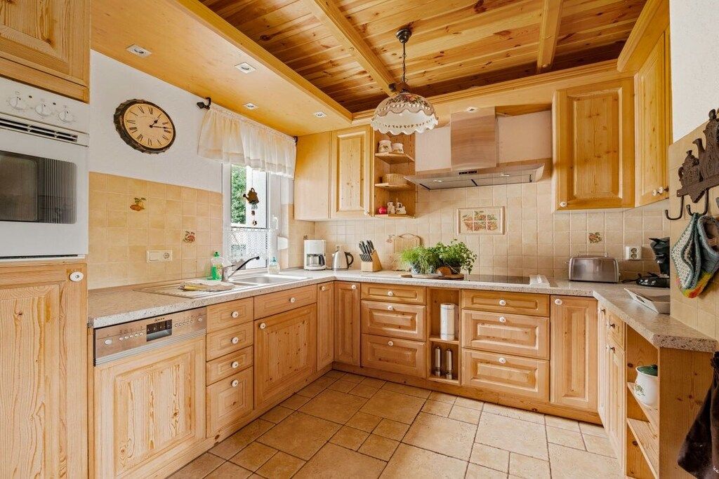 A kitchen with wooden cabinets, a built-in oven, a sink, and a hanging light fixture.