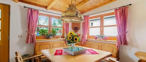 Un interior de madera con una mesa, sillas y una lámpara colgante.