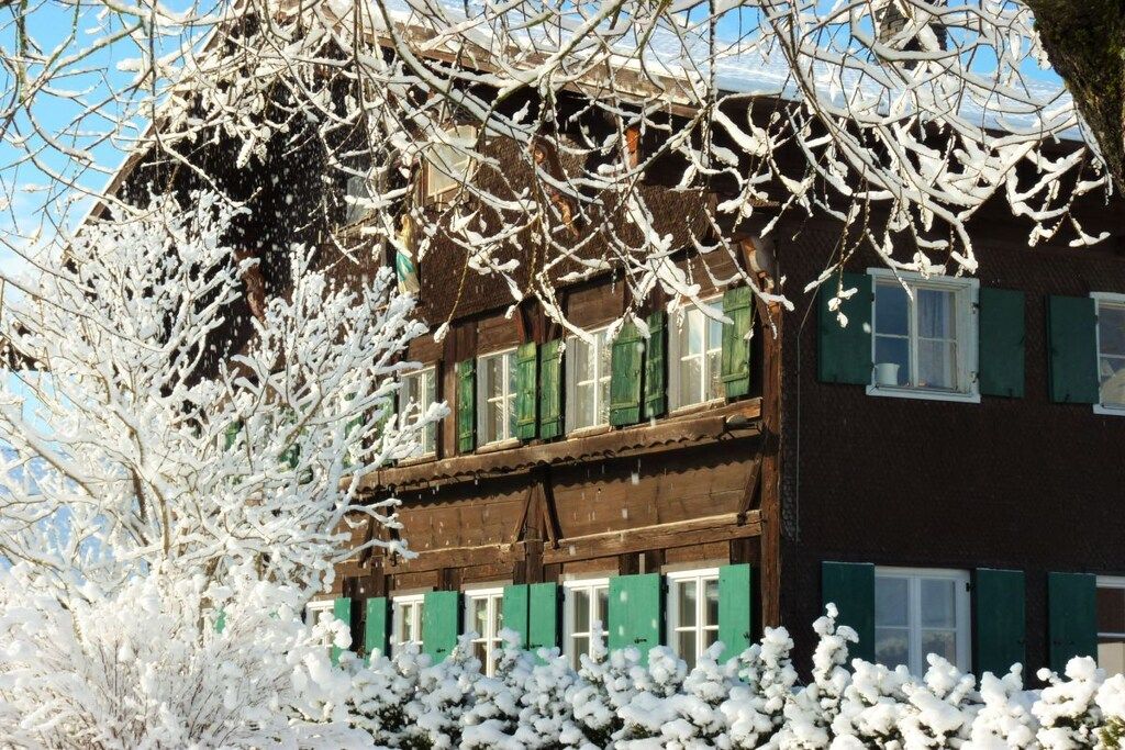 Een gebouw met twee verdiepingen, groene luiken en een houten gevel.