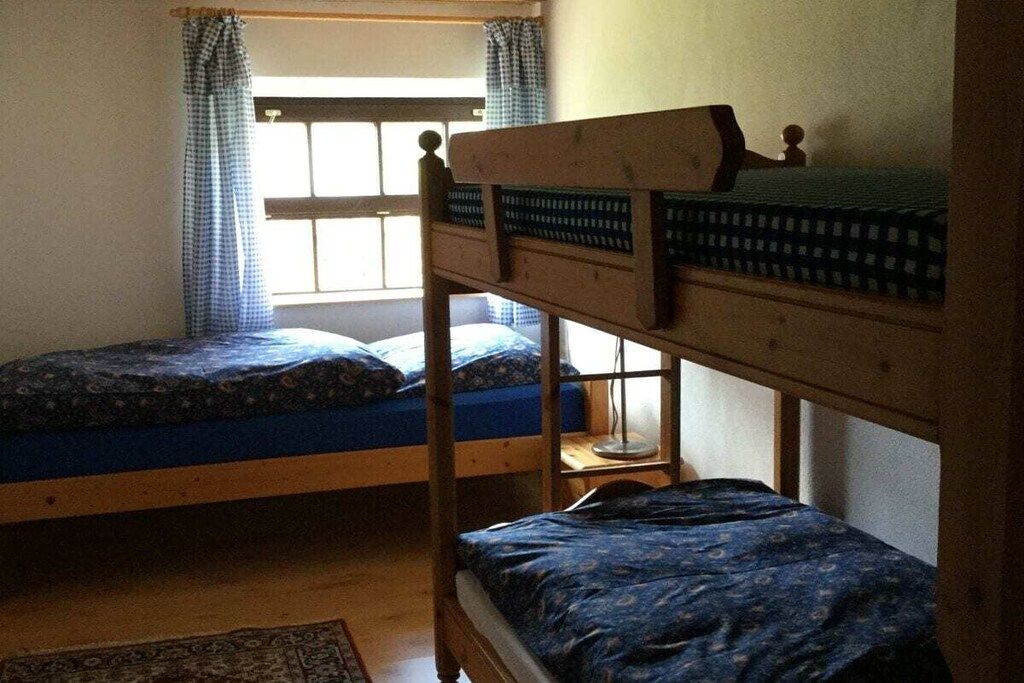 Ein Zimmer mit zwei Etagenbetten, einem fenster mit Vorhängen und einem Holzboden.