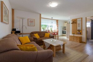 Ein Wohnzimmer mit einer Sofagarnitur, einem Couchtisch und einem Essbereich mit Stühlen.