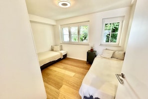 Une chambre avec deux lits, une petite table et une fenêtre.
